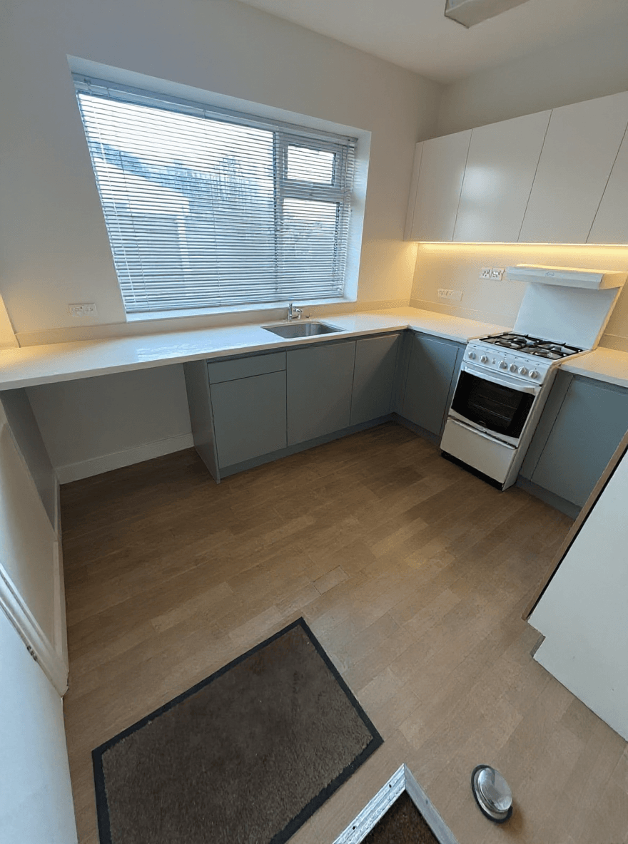 AFTER: Light two-tone cabinetry, quartz-look worktops, brass hardware
